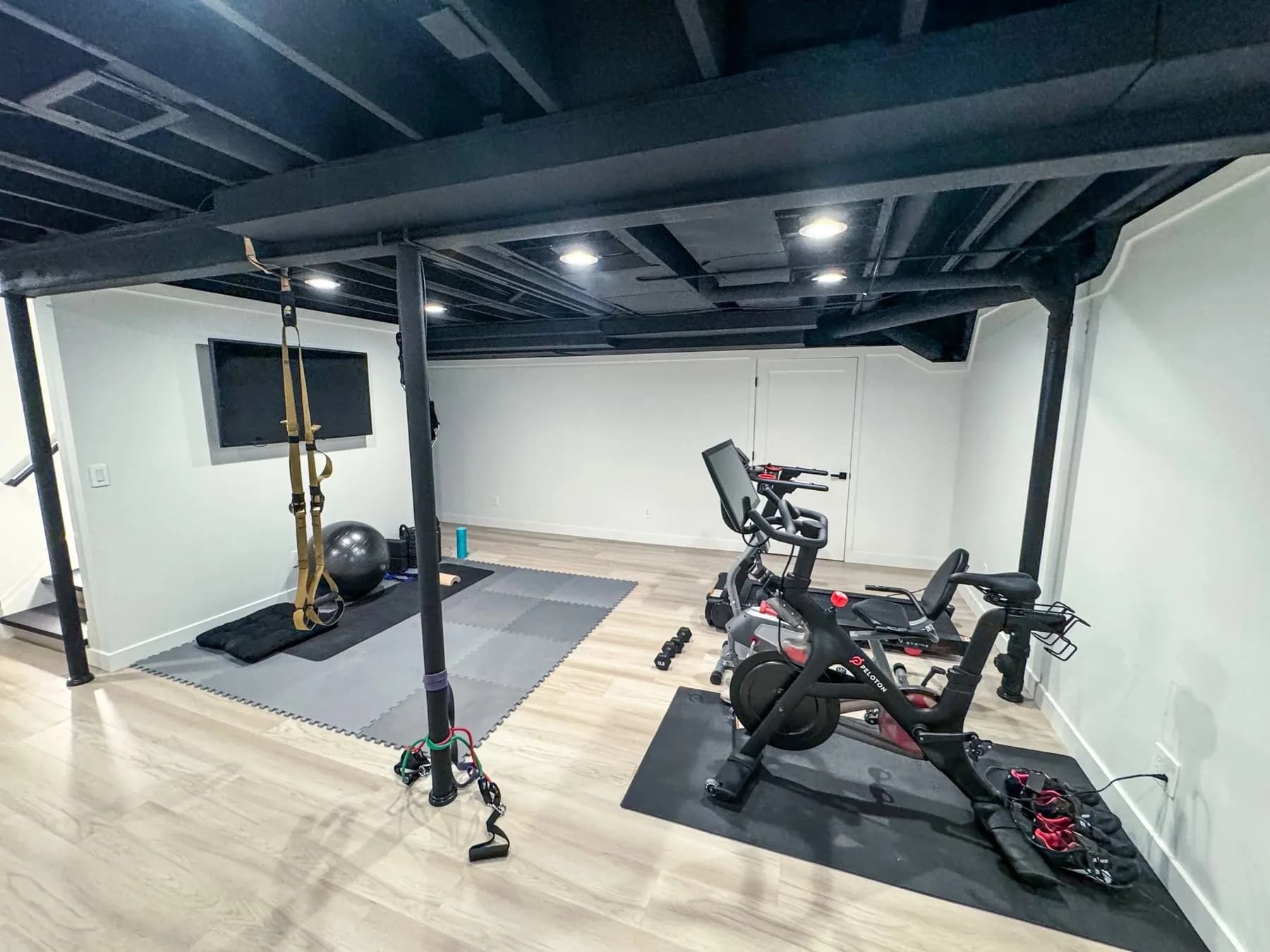 Basement home gym with a squat rack, exercise bike, and rubber flooring