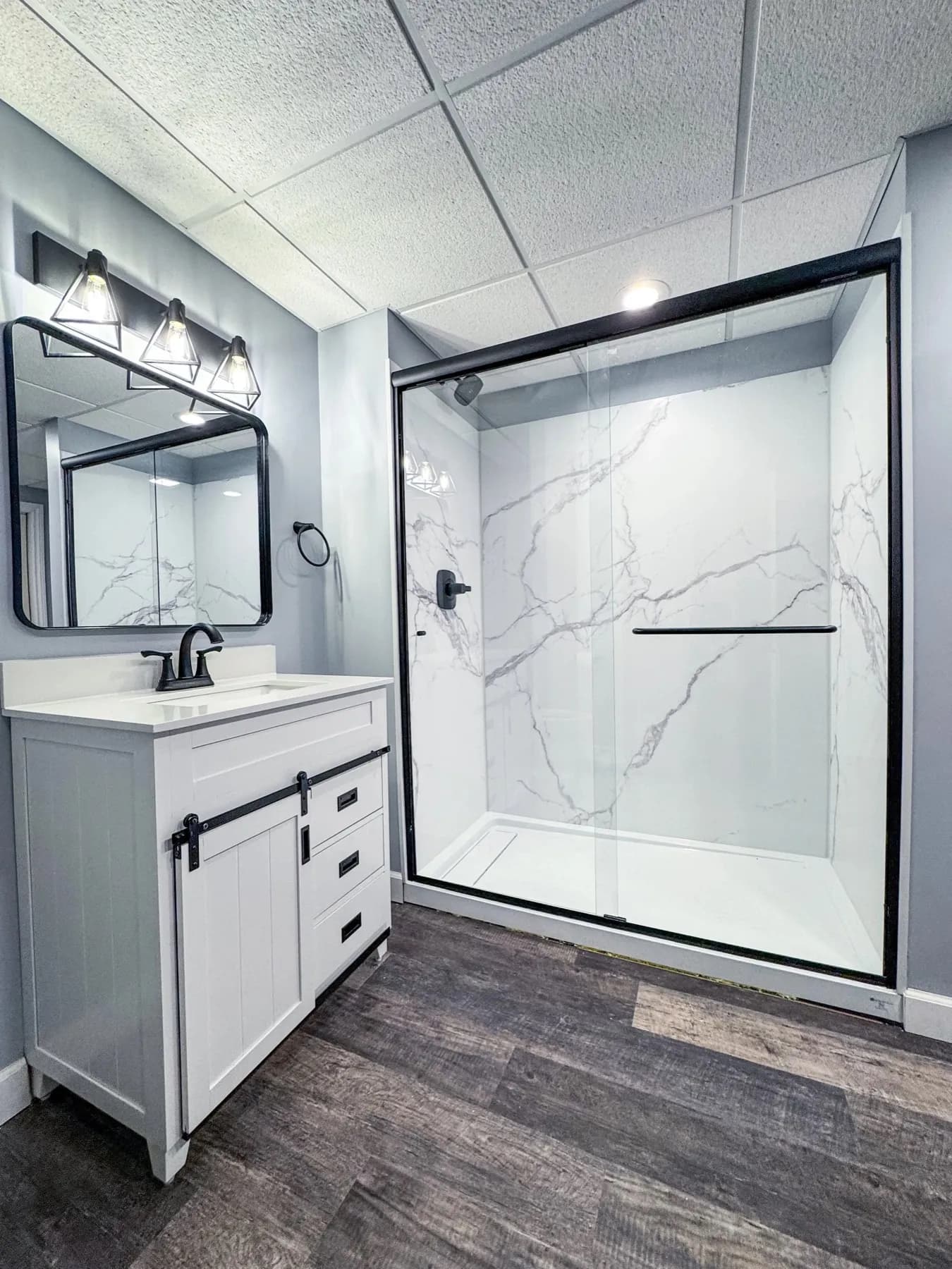 Bathroom with a marble-look walk-in shower, white vanity, and a black painted ceiling