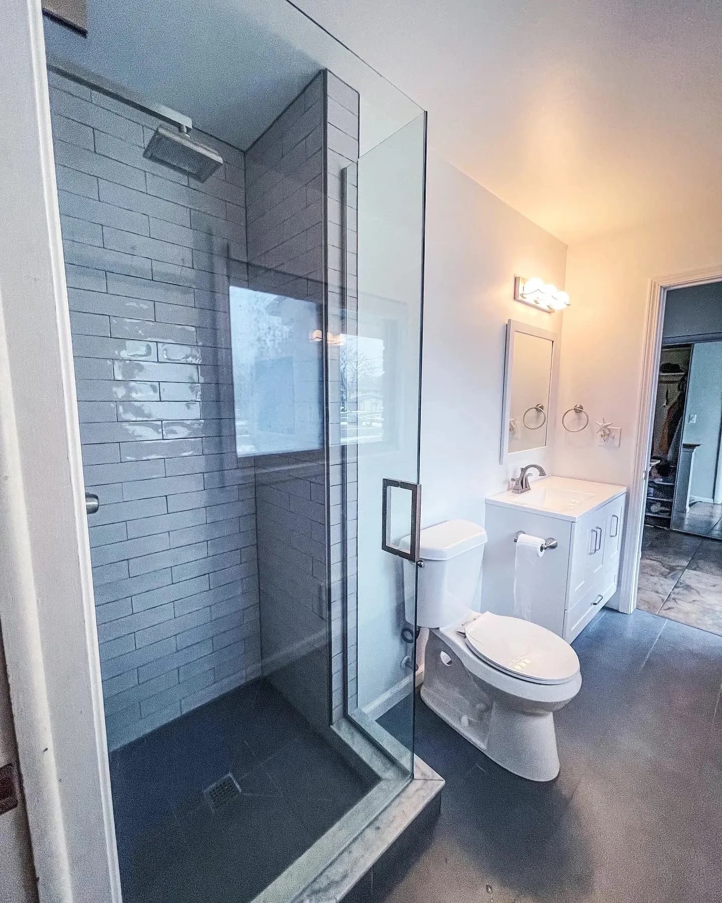 Bathroom with a glass walk-in shower and dark tile surround