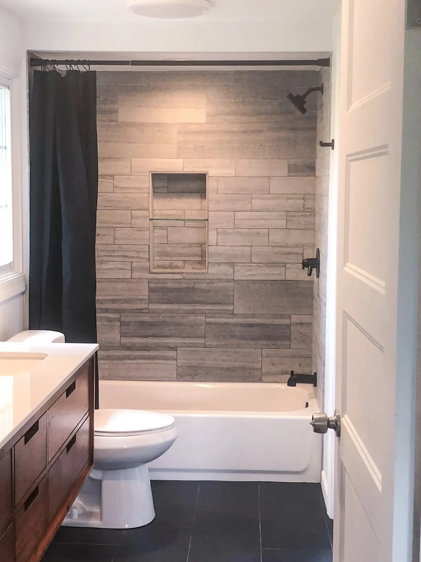 Bathroom with a tiled tub and shower combination and a dark vanity