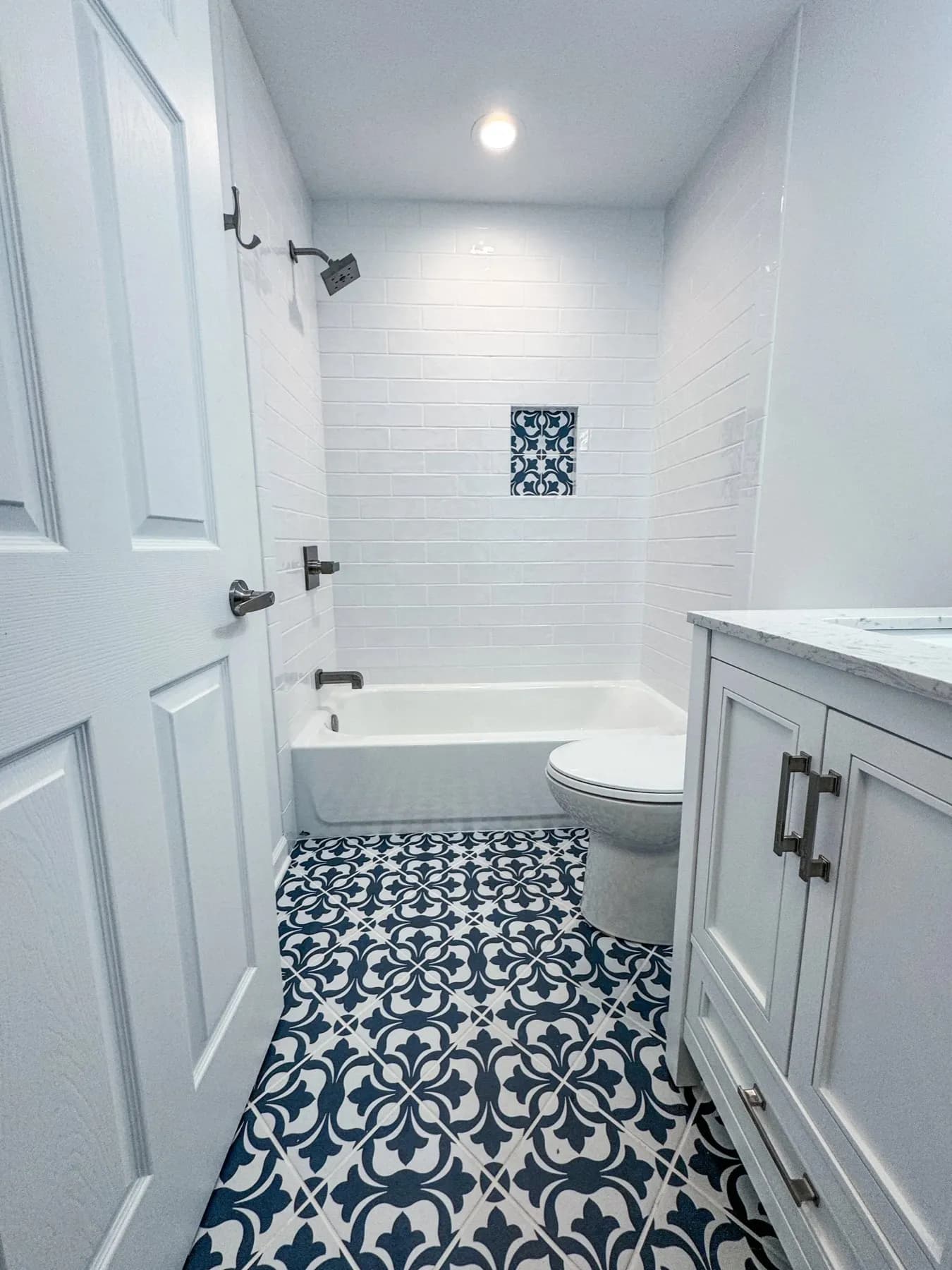 Bathroom with patterned encaustic-look floor tile, a white vanity, and a tub