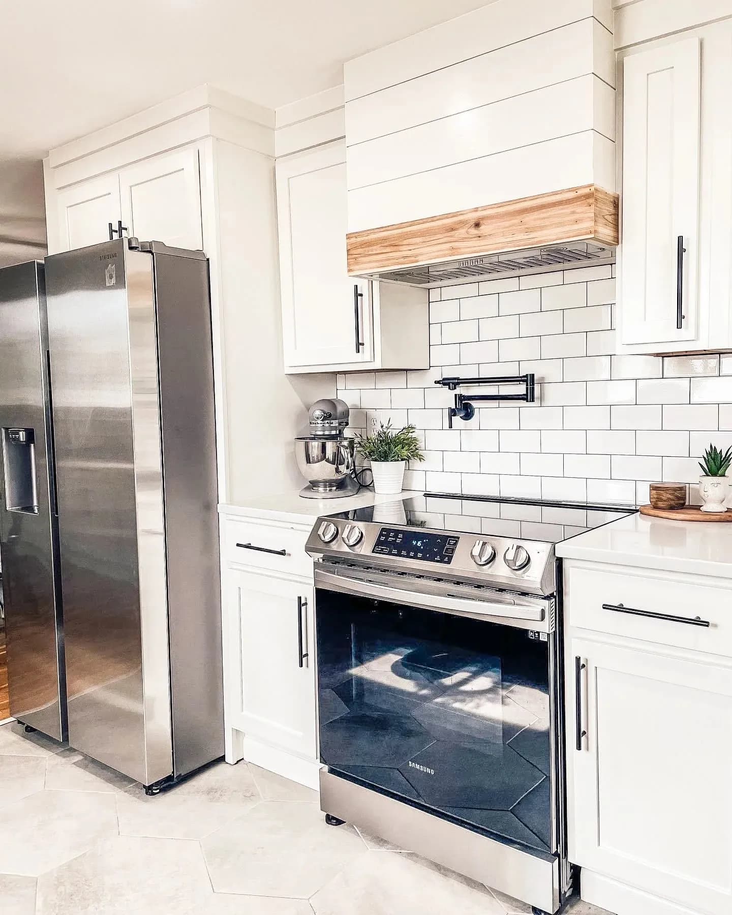 Remodeled kitchen with white shaker cabinets, white subway tile backsplash, a wood range hood, and a stainless steel range