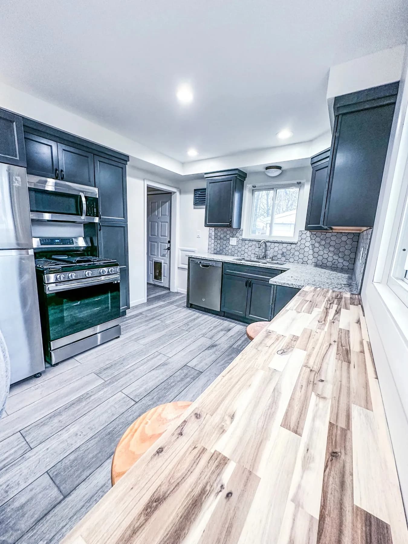 Kitchen renovation mid-install with dark cabinets set and new flooring being laid