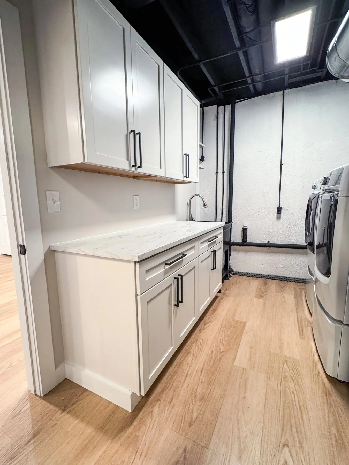 Laundry room with white cabinets, a wood folding counter, and a black painted ceiling