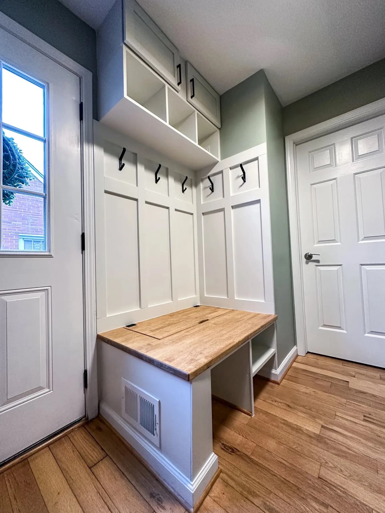 Built-in mudroom lockers with a bench, hooks, and a butcher block top